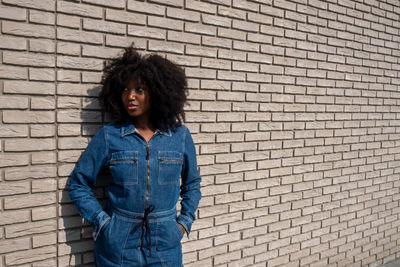 Young woman standing against brick wall