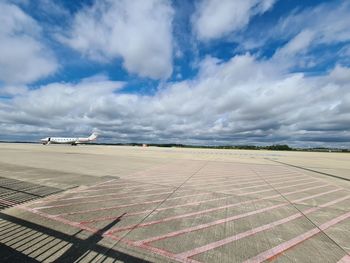 View of airport runway against cloudy sky