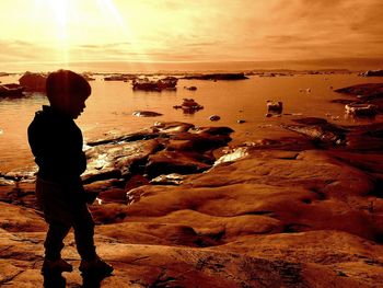 Silhouette man standing at beach during sunset