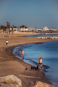 People on beach against clear sky