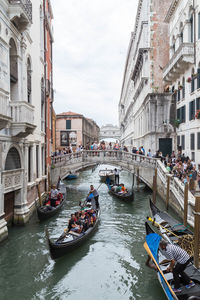 People on boats in city against sky