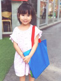 Portrait of smiling girl standing on footpath