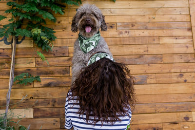 Woman with dog against wooden wall