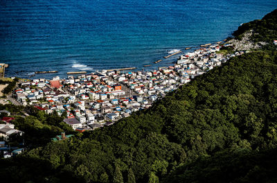 High angle view of townscape by sea against blue sky