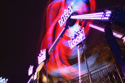 Low angle view of illuminated carousel against sky at night