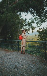 Portrait of boy standing by tree against plants