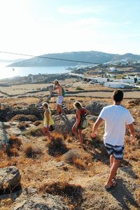 High angle view of young men and women walking on mountain against sky