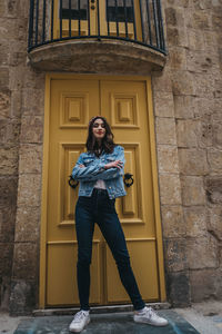 Portrait of young woman standing against building