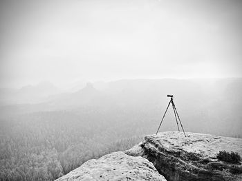 Tripod on the peak ready for photogrpahy. exposed rocky view point. misty rainy autumnal day 