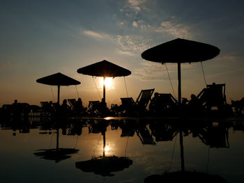Silhouette people by swimming pool in lake against sky during sunset