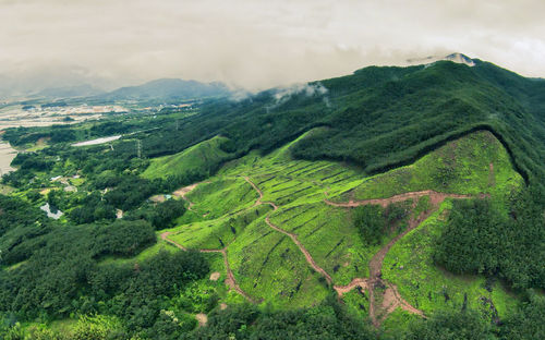 Aerial view of green landscape and mountains against sky