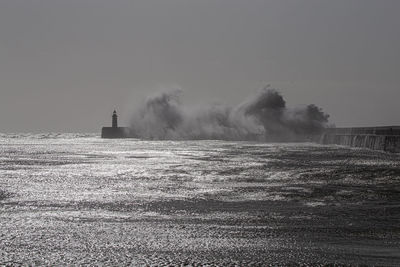 Lighthouse on field by sea against sky