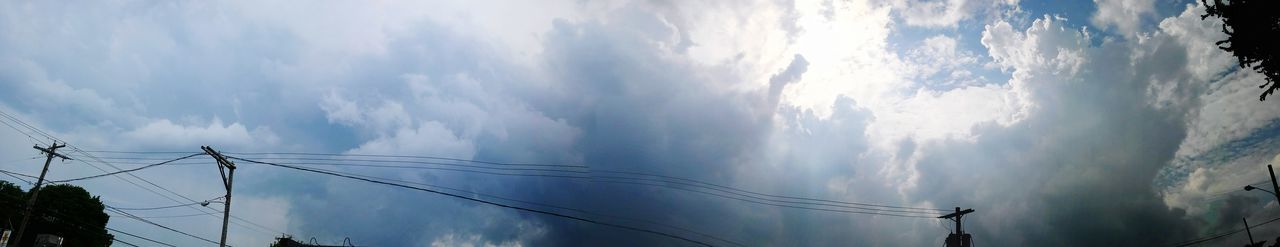 Low angle view of electricity pylon against cloudy sky