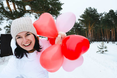 Portrait of young woman with balloons against sky