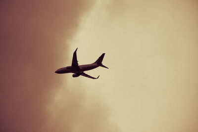 Low angle view of silhouette airplane flying against sky during sunset