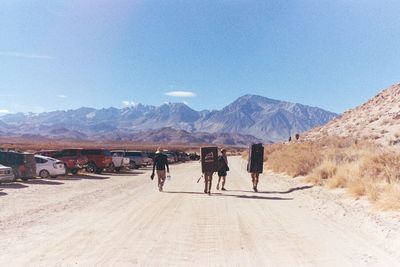 Rear view of people walking on sand at desert