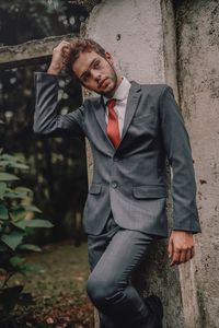 Portrait of young man standing against wall