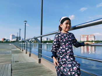 Young woman standing by railing against bridge