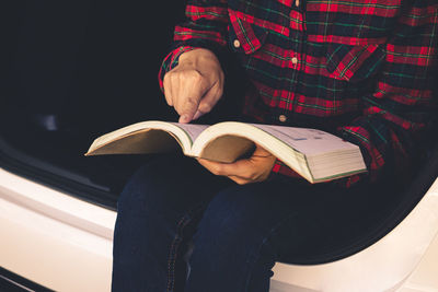 Midsection of man reading book