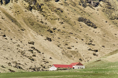 Small barns at the foot of a steep mountain slope with scattered rocks