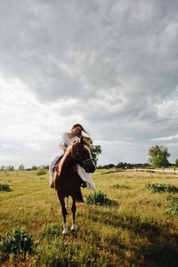 Young woman riding horse on field