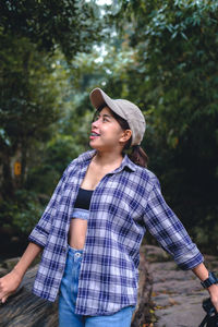 Portrait of young woman standing against trees