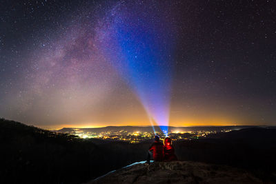 People holding flashlight against sky