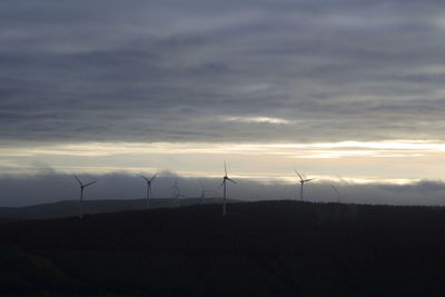 Windmill on field against sky at sunset