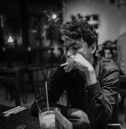 Man holding cigarette while sitting in restaurant