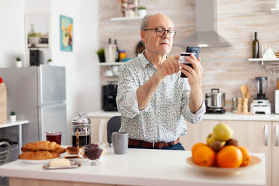 Senior man holding credit card while using laptop at home