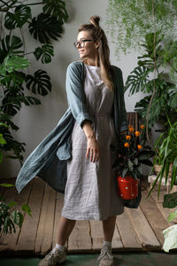 Full length of woman standing against potted plants