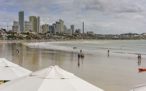 Modern city by sea against sky