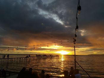 Silhouette people by sea against sky during sunset