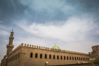 Low angle view of mosque against cloudy sky