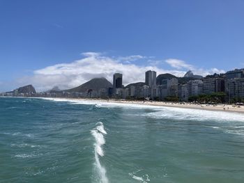 Sea by buildings in city against sky