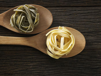 Close-up of tagliatelle pasta in wooden spoons on table