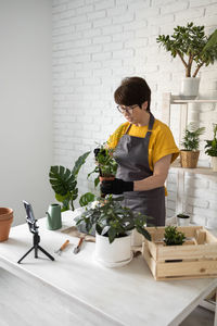 Side view of woman holding potted plant on table