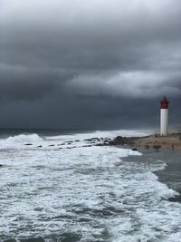 Lighthouse by sea against sky