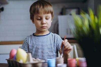 Cute little boy colouring eggs for easter