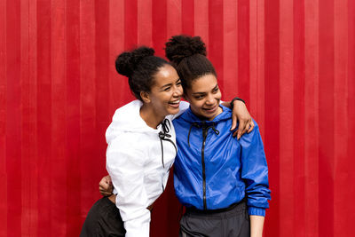 Cheerful young women standing against red cargo container