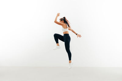 Full length of woman dancing against white background