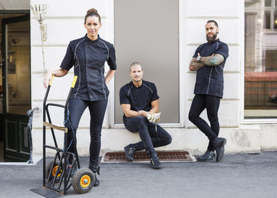 Full length portrait of workers standing outside candy store