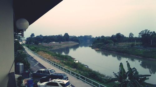 Cars on road by river against sky in city