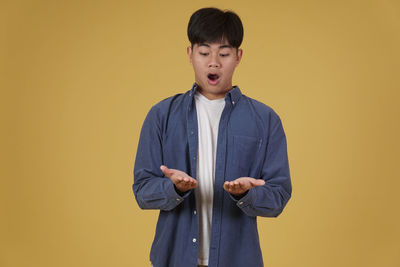 Young man looking away against orange background