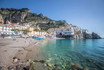 View of houses on mountain by sea against clear blue sky during sunny day