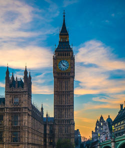 Clock tower amidst buildings in city against sky