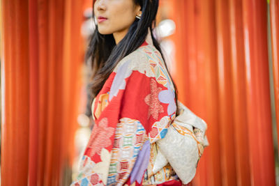 Young woman looking away while standing outdoors