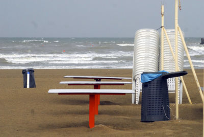 Deck chairs on beach against sky