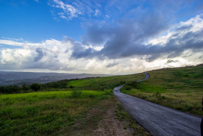 Road leading towards landscape against sky