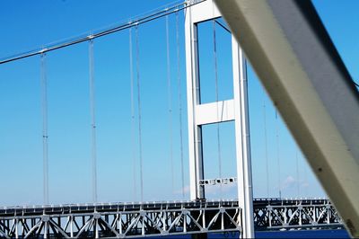 Low angle view of suspension bridge against clear blue sky